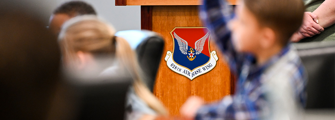 Military homeschoolers of the Lowcountry students raise their hands to ask questions regarding naval service during a wing leadership building tour at Joint Base Charleston.